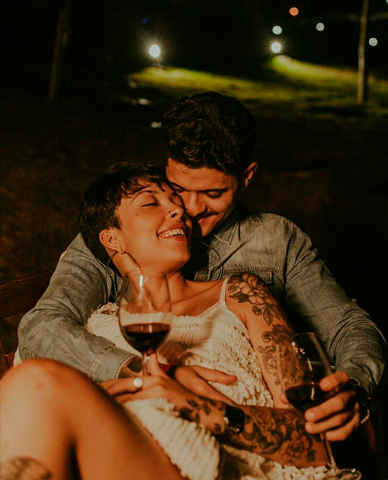 Casal sorrindo abraçado com taças de vinho no Container Du Lago